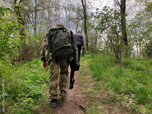 Fishermen lift with backpacks and fishing rods, return home after fishing.