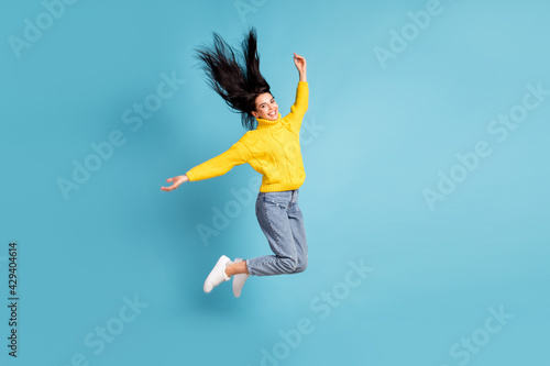 Full length body size side photo of brunette jumping high throwing hair in the air isolated on vivid blue color background