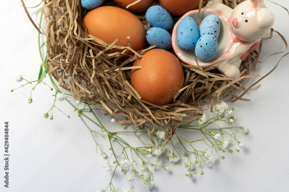 Fototapeta premium Natural eggs with Easter eggs, feathers in a nest on a dark background. Top view, Happy Easter. Easter Holiday,