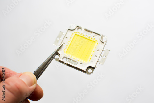 Wallpaper Mural Led chip isolated on white background. Hand holding diode in pliers Torontodigital.ca