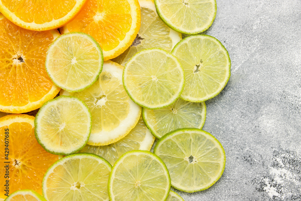 the background with cut citrus fruits of round form, sliced oranges, limes and lemons at at the grey beton background, copy space for text