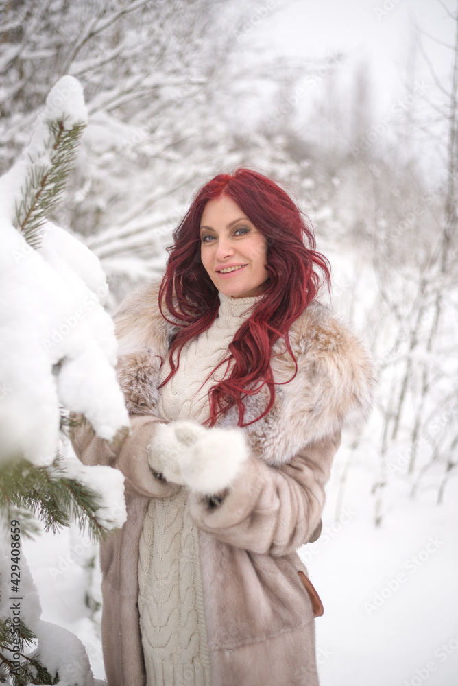 portrait of a young beautiful women with long red hair in winter forest of snowy park portrait of a young beautiful women with long red hair in winter forest of snowy park