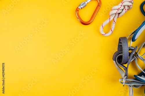 Climbing adventure equipment flat lay view. Top view of extreme mounteneering tools like helmet, carabiner, rope, gloves, radio, harness, figure eight. Concept on the trendy yellow background. photo