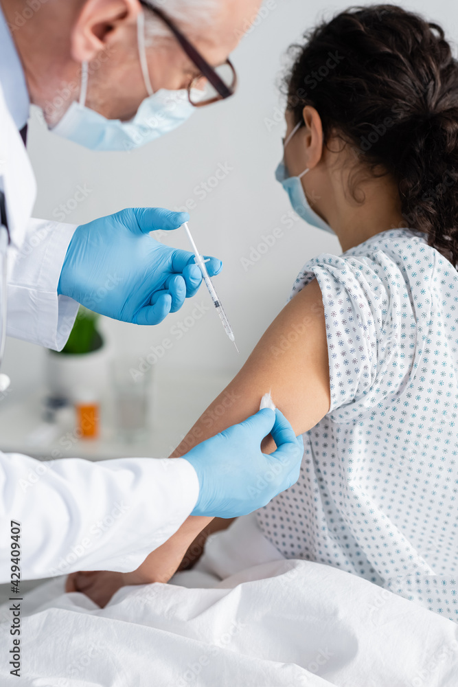 doctor in medical mask doing injection of vaccine to african american woman doctor in medical mask doing injection of vaccine to african american woman