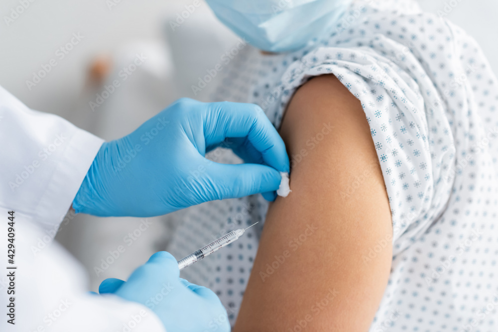 Fototapeta premium partial view of doctor in latex gloves doing injection of vaccine to woman in medical mask