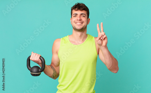 fitness man smiling and looking friendly, showing number two or second with hand forward, counting down photo