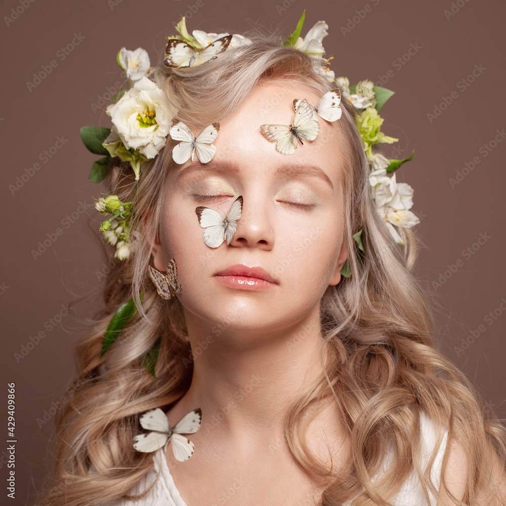 Healthy young woman face. Blonde female model with curly hair, white gentle flowers and  butterfly close up portrait