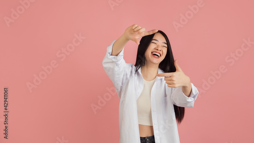 Asian young woman's portrait on pink studio background. Concept of human emotions, facial expression, youth, sales, ad.