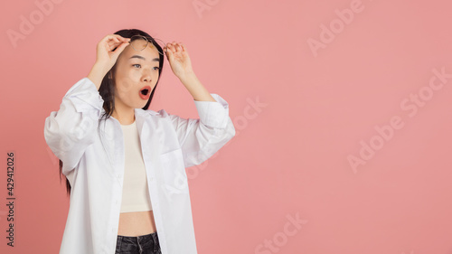 Asian young woman's portrait on pink studio background. Concept of human emotions, facial expression, youth, sales, ad.