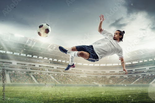 Male soccer, football player catching ball in jump at the stadium during sport match on dark sky background