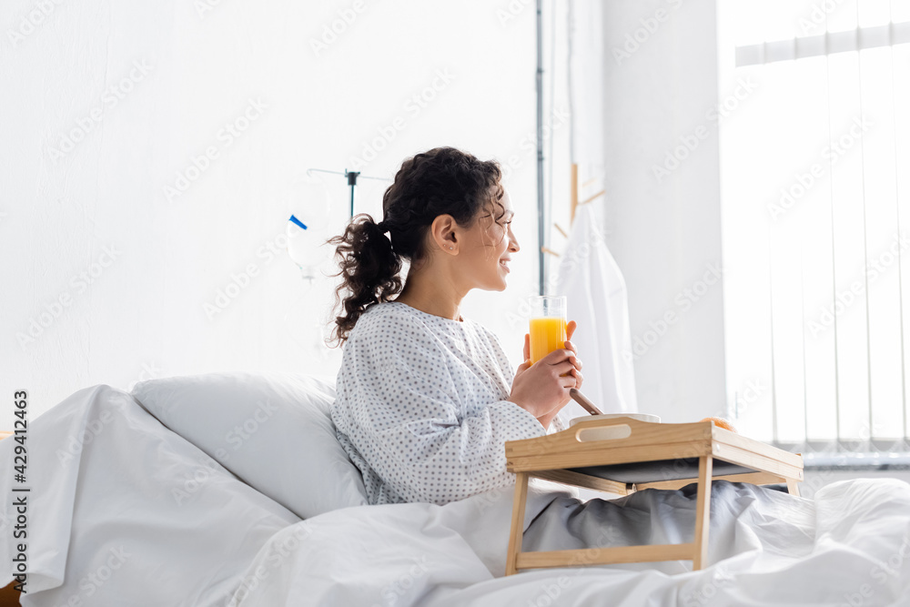 smiling african american woman looking away while holding orange juice during breakfast smiling african american woman looking away while holding orange juice during breakfast