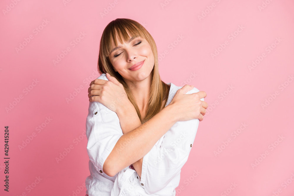 Photo of inspired girl hands embrace shoulders close eyes wear white blouse isolated pink color background Photo of inspired girl hands embrace shoulders close eyes wear white blouse isolated pink color background