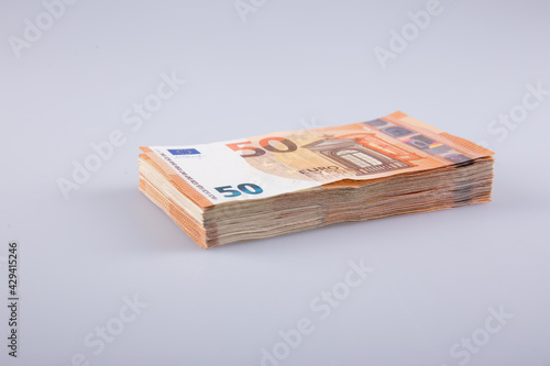 A stack of clear 50 euro banknotes on a gray background. 