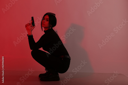 Young woman holding a pistol with red filter photo