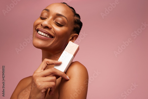 Woman with melanin skin showing a skincare product photo