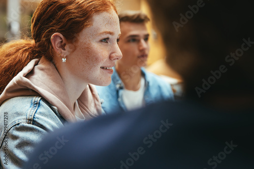 Cheerful girl studying with friends in library photo