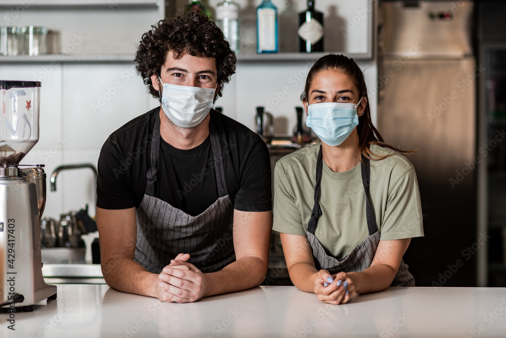 Team work spirit.Millennial business team wear protective masks, posing in coffee shop during corona virus.
