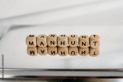 Word manhunt made by wooden cubes with reflection photo