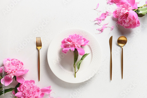 Festive spring table setting with pink peony flowers on a white table. View from above. Banquet Invitation.