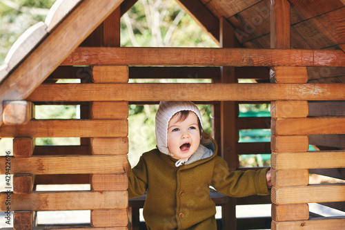 Outdoor portrait of cute toddler kid having fun on playground, wearing warm jumpsuit