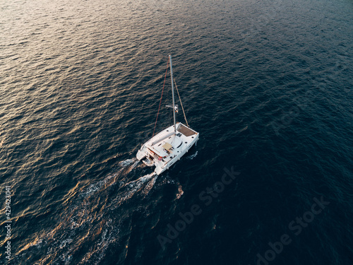 White sailing catamaran yacht sails in the blue sea © Nadtochiy