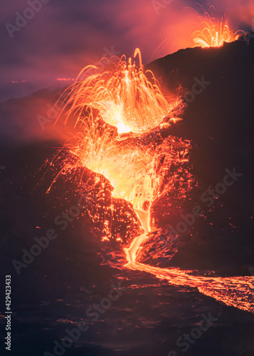 Lava exploding in from the volcano, with bright lights and lava bits erupting from the crater in Iceland. 