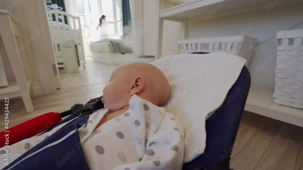Baby sleeping in rocking chair while mom does household chores, 1.5 month old infant in baby bouncer. High quality 4k footage