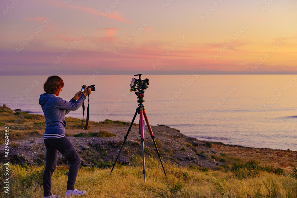 Woman with camera take travel photo at sunset