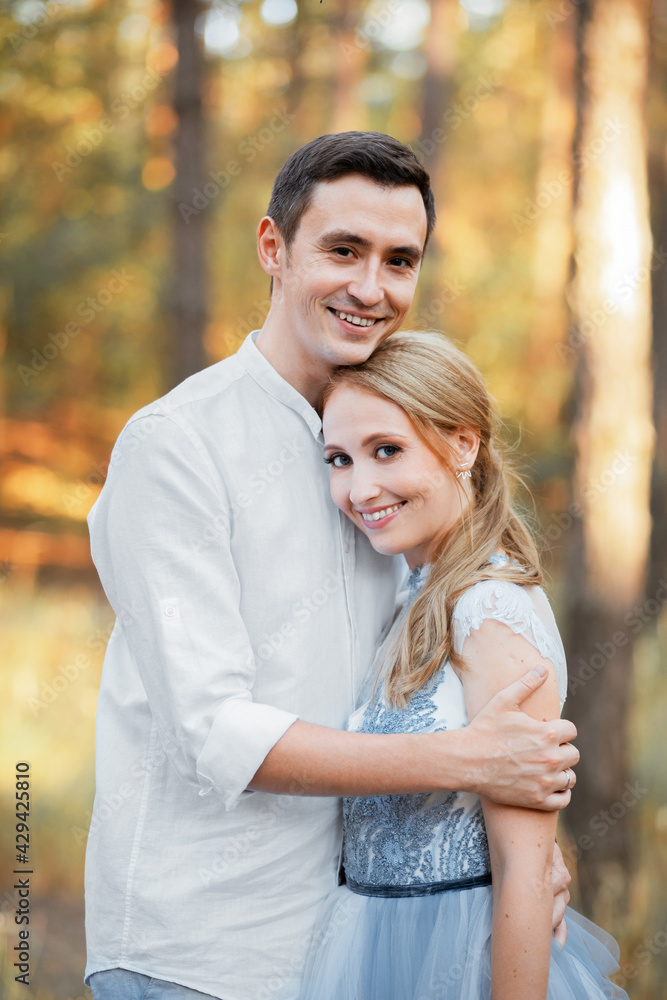 Happy young couple on a walk in the forest at sunset. The bride is wearing a blue wedding dress. Happy young couple on a walk in the forest at sunset. The bride is wearing a blue wedding dress.
