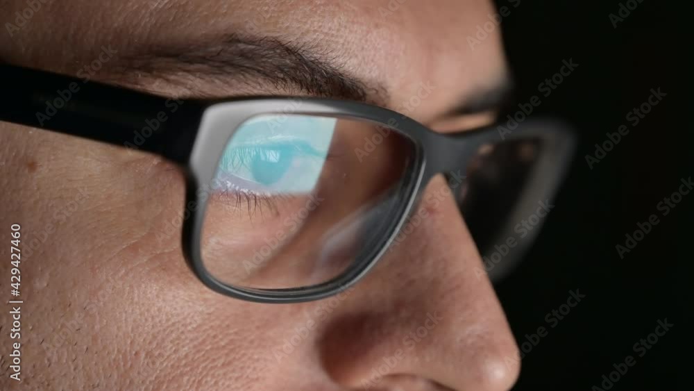Close up portrait of a software engineer who is working: the eyes are focused on the screen where he is processing the instructions of the program. On the lens of the glasses we see their reflection. Close up portrait of a software engineer who is working: the eyes are focused on the screen where he is processing the instructions of the program. On the lens of the glasses we see their reflection.