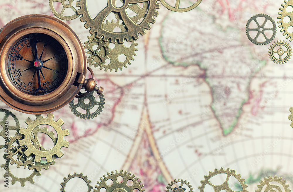 Fototapeta premium Compass with gears and cogs and an old map.