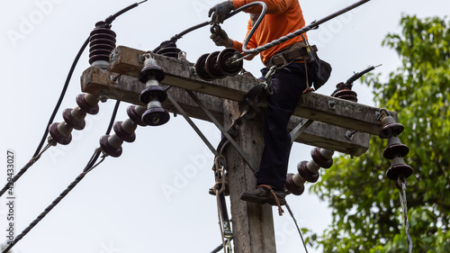 Rural electric poles are being repaired by electricians installing wires to connect. The tops of the electric poles are attached to the insulator. It is a job at a high rate.