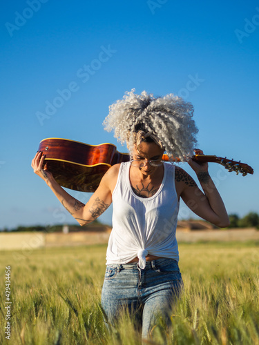 Mujer joven con una guitarra en un campo de trigo 