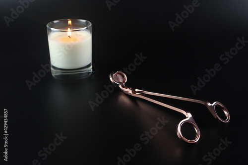 Fotografija rose gold wick trimmer is put on the black table with a glass of aroma scented s