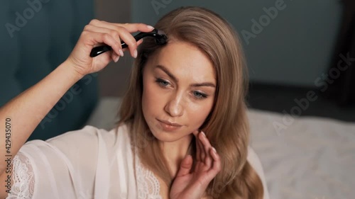 Pretty long-haired blonde woman massages her head with a mesoscooter photo