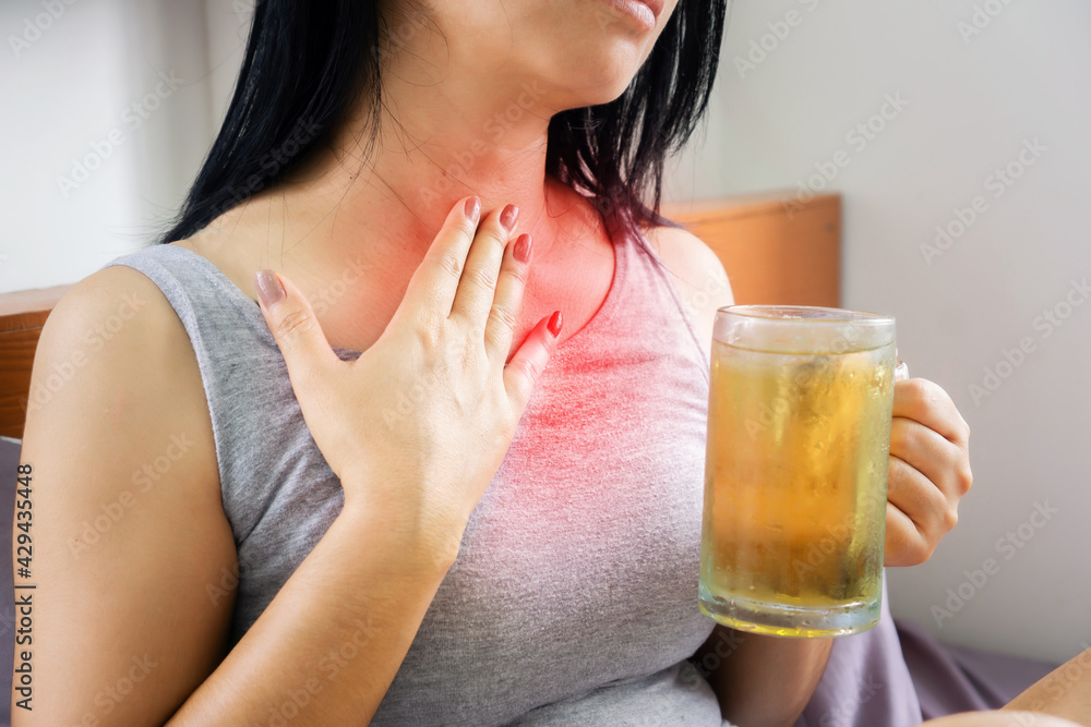Asian woman drinking beer having problem with GERD , acid reflux, and heartburn with gastritis from alcohol Asian woman drinking beer having problem with GERD , acid reflux, and heartburn with gastritis from alcohol
