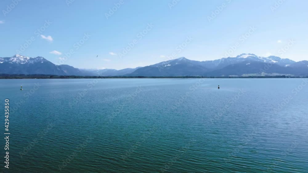 Scenic low flight above Bavaria's most famous lake Chiemsee in the rural countryside with a beautiful sky, clear blue water and the alps mountains breathtaking in the background on a sunny day. Scenic low flight above Bavaria's most famous lake Chiemsee in the rural countryside with a beautiful sky, clear blue water and the alps mountains breathtaking in the background on a sunny day.