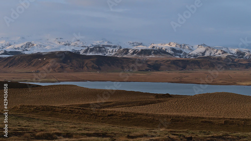 Beautiful panoramic view of the snow-capped foothills of ice cap Mýrdalsjökull, covering volcano Katla, in the evening light viewed from Dyrhólaey peninsula on the southern coast of Iceland.