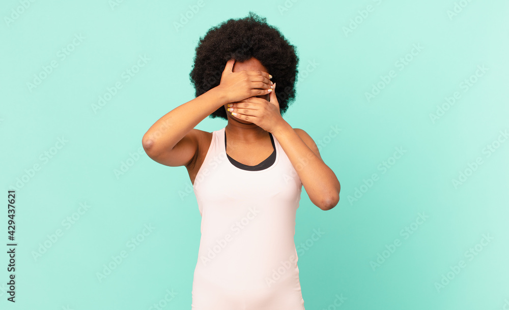 black afro woman covering face with both hands saying no to the camera ...