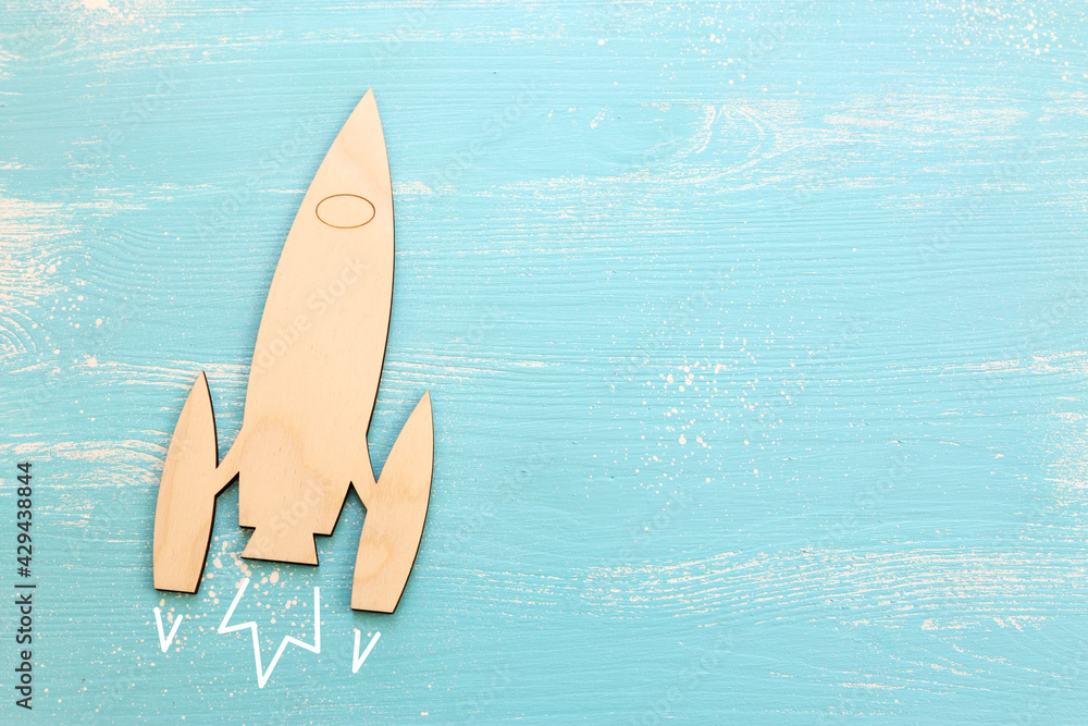 Top view image of wooden rocket toy over pastel background.