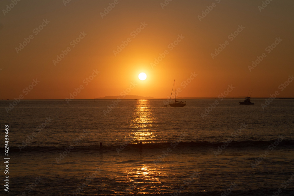 sunset on the beach with the silhouette of a boat