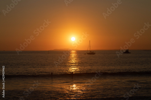 sunset on the beach with the silhouette of a boat