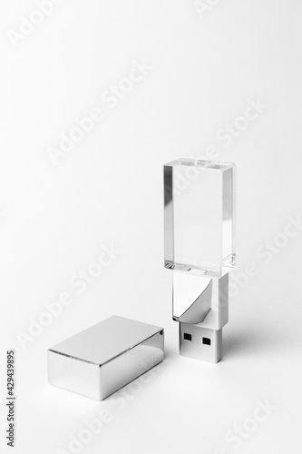 Glass USB stick with a metal cover on a gray background. Copy space. Vertical close-up photo.