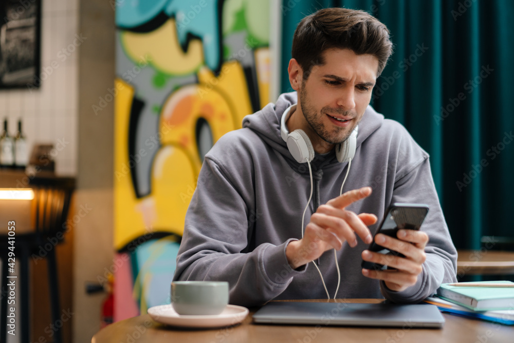 Happy young brunette man holding mobile phone Happy young brunette man holding mobile phone