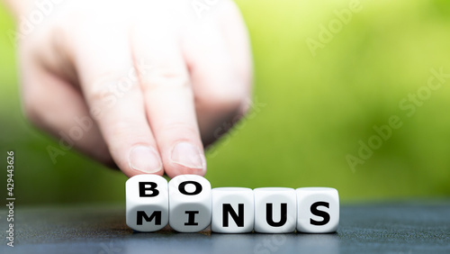 Hand turns dice and changes the word "minus" to "bonus".
