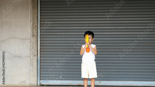 Asian child boy playing water gun toy at home in Songkran day with happy relaxing face. Concept of happy family activity at home, freedom fun. Songkran festival day 2021, new normal Covid 19.