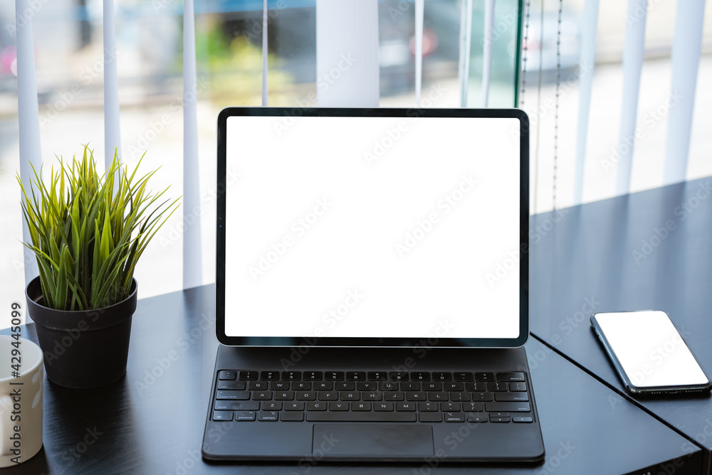 Work area with tablet white screen placed on a black wooden table. Mock up. Work area with tablet white screen placed on a black wooden table. Mock up.