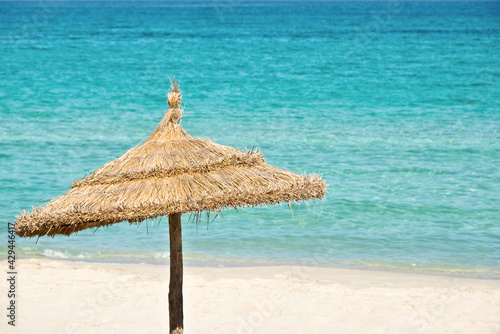 Palapa  hawaiian straw thatched beach umbrella on a perfect beach  tropical travel concept