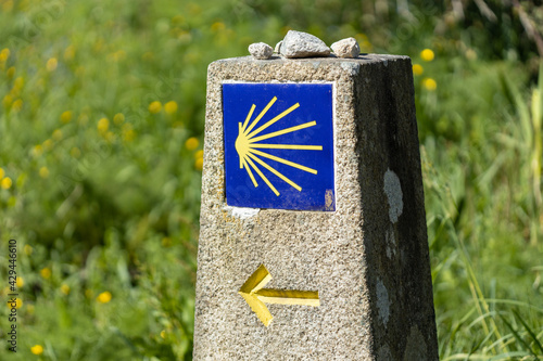 Camino de Santiago sign on stone monolith with green grass background photo