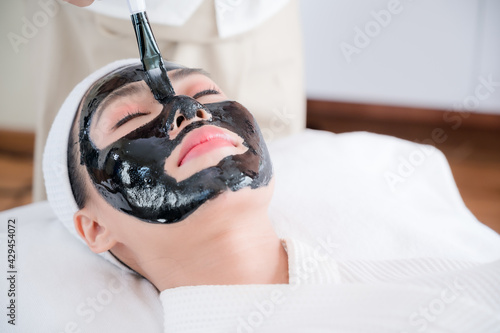 Professional masseuses in spa salons use spa mud brushes to give Asian beauties facial treatments photo